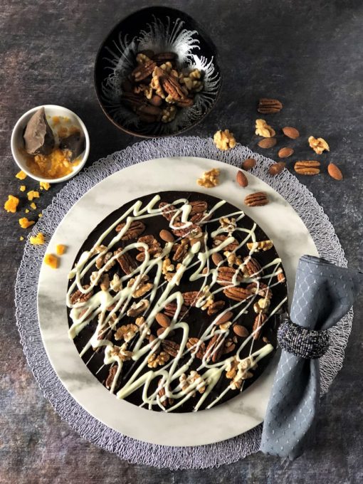 dark chocolate pizza with pecans almonds walnuts on white plate