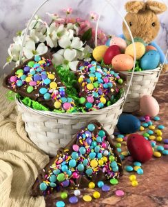 3 chocolate pizza slices with pastel candies in a white basket on a table